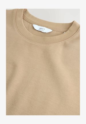 Beige Baumwollcrewneck-Sweatshirt mit geripptem Kragen und subtiler Textur. Das Etikett trägt die Aufschrift "NEXT" mit "REGULAR FIT" darunter.