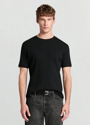 T-shirt nera a maniche corte con motivo a coste e scollo tondo. La trama del tessuto è morbida, con righe verticali. Indossata con jeans scuri e cintura.