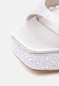 Fehér platform szandál négyzet alakú orral és csillogó, strasszos pánttal és talp szélén.
