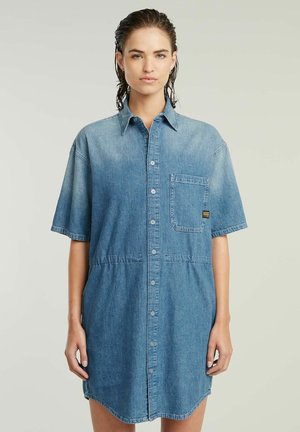 Sukienka koszulowa z denimu w jasnoniebieskim kolorze, z zapięciem na guziki, krótkimi rękawami, kieszonką na piersi oraz subtelnym przetarciem na dole.