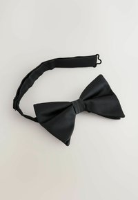Black bow tie with ribbed texture, featuring a central band. Attached to an adjustable black strap for secure fitting.