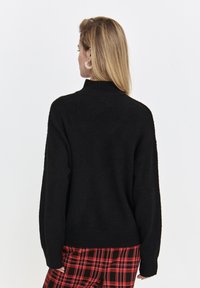Czarny, oversize sweter z wysokim kołnierzem i długimi rękawami. Teksturowana dzianina, wykończona prążkowanym dołem.