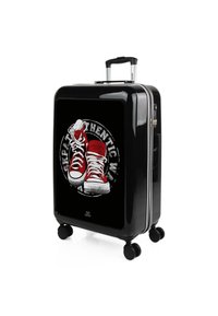 Maleta rígida negra con acabado brillante, que presenta un gráfico de zapatillas rojas y blancas, cuatro ruedas giratorias y un mango extensible.