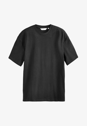 T-shirt nera in cotone con maniche corte, collo a giro, vestibilità ampia e texture liscia. Nessun motivo o accentuazione visibile.
