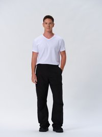 Hvid kortærmet V-hals t-shirt parret med sorte cargo bukser, der har lommer og en løs pasform. Modellen står foran en ensfarvet baggrund.