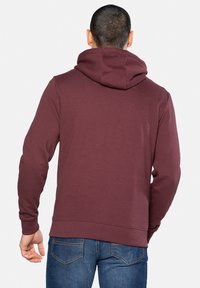 Bordeaux hoodie met een gladde textuur, lange mouwen en een ontspannen pasvorm. Bevat een buidelzak en ribgebreide mouwen en zoom.