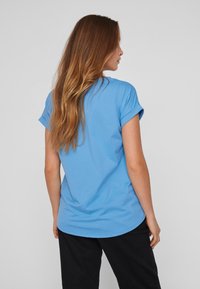 T-shirt bleu à manches courtes avec ourlets roulés, fabriqué dans un tissu léger et doux. Présente une coupe décontractée et un ourlet arrondi.