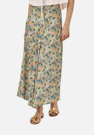 Falda midi floral con fondo durazno, que cuenta con hojas verdes y flores azules. Fabricada en una tela ligera con un diseño suelto, combinada con sandalias planas.