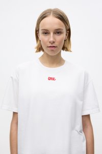 Witte katoenen T-shirt met korte mouwen, featuring een rood "ONE" logo gestikt op de voorkant. Eenvoudig ontwerp en relaxte pasvorm.