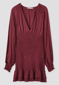 Top burdeos de manga larga con cuerpo fruncido, escote en V profundo y dobladillo con volantes. Tejido suave con detalles texturizados en las mangas y la cintura.