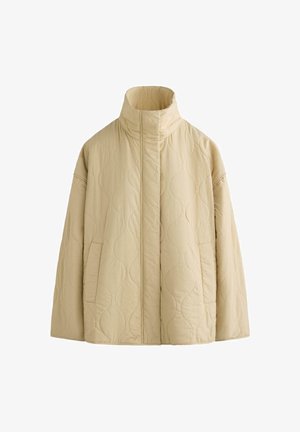 Bézs steppelt dzseki magas gallérral, elülső zsebekkel, hosszú ujjal és rejtett elülső zárral, fehér háttéren bemutatva.