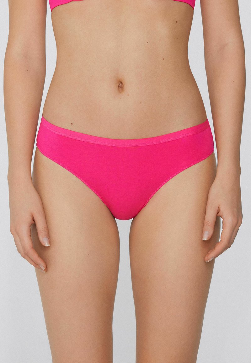 Růžové bikinové kalhotky s hladkou texturou, nízkým pasem a širokým pásem. Materiál je elastický a přiléhavý, vhodný na plavky.