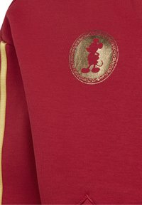 Czerwony sweter z gładką teksturą, z emblematem złotego Mysia Mickey oraz kremowymi pasami po bokach. Zauważalny detal przeszycia u dołu.