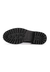 Suela de bota de goma negra con surcos profundos, que presenta un patrón de agarres rectangulares y hexagonales para tracción y estabilidad.