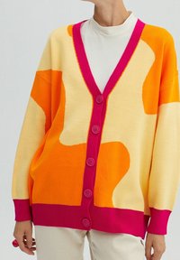 Dzianinowy kardigan w kolorach żółtym, pomarańczowym i różowym. Posiada dekolt w serek, luźny fason i pięć fioletowych guzików z przodu. Gładka faktura.