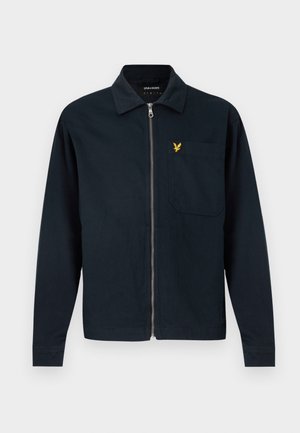 Temno modra jakna z zadrgo, ovratnikom in žepom na prsih z majhnim rumenim logotipom orla na levi strani.