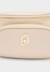 Borsa sintetica beige con due scomparti con zip, hardware in tonalità oro e logo impresso. Texture liscia e design arrotondato per una facile maneggevolezza.