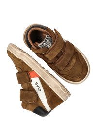 Brown suede sneakers with two Velcro straps, white and orange accents, cream rubber sole, and printed logo on the tongue.