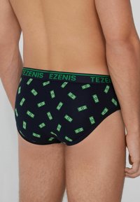 Culotte pour homme avec une base bleu marine foncé, ornée d'un motif de billets de banque verts. Tissu doux et taille élastique avec le logo "TEZENIS".