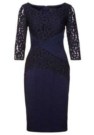 Marineblauwe jurk tot over de knie met bloemenkant aan de lange mouwen en het lijfje, voorzien van een geplooid taillepaneel met kleine kralenversieringen.