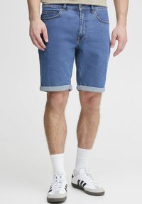 Zili denim šorti ar sarullētām malām, piecu kabatu dizains un kontrastējoša šuvuma. Nēsāti ar baltām potīšu zeķēm un sporta apaviem.