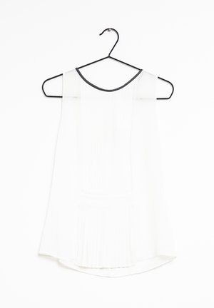 Witte mouwloze top met een geplooide textuur, ronde halslijn met zwarte bies, hangend aan een zwarte hanger tegen een witte achtergrond.