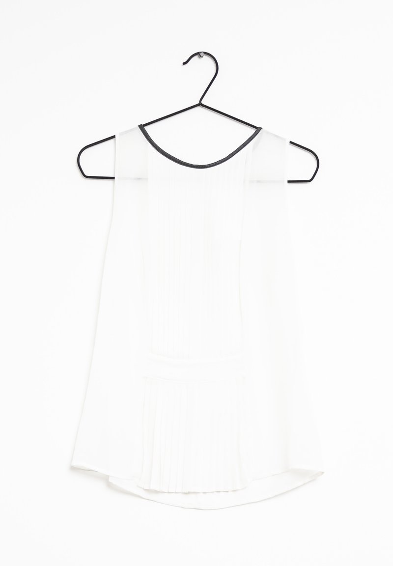 Haut sans manches blanc avec une texture plissée, encolure ronde avec bord noir, suspendu sur un cintre noir contre un fond blanc.