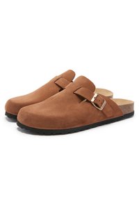 Sabots en daim marron avec un bout arrondi, sangle ajustable, semelle intérieure en liège naturel et semelle extérieure en caoutchouc noir texturé. Pas de motifs visibles.