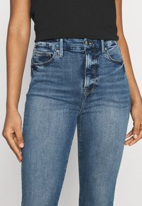 Högmidjade blå denimjeans med slim fit, femfickorsdesign, ljus blekning och kontrasterande sömmar för detalj.