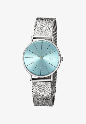 Montre argentée circulaire avec un cadran bleu clair, bracelet en maille argentée fine et index des heures noirs ; design minimaliste avec un bracelet texturé.