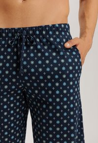 Navyblå mönstrade pyjamasbyxor med blommönster och diamantmotiv, med elastisk midja och sidofickor. Slät tygkänsla.