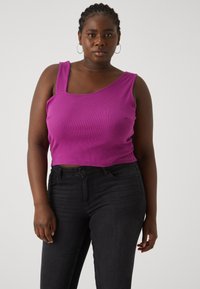 Purple ribbed tank top with a square neckline and thick straps, paired with dark skinny jeans. The fabric appears soft with slight texture.
