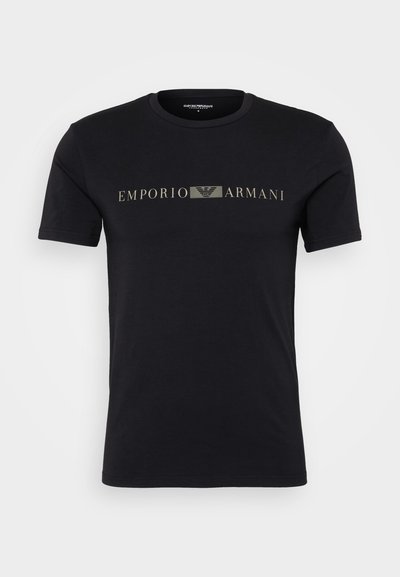 Musta puuvillapaita lyhyillä hihoilla, jossa on kultainen "Emporio Armani" -logo rinnassa ja pyöreä kaula-aukko. Silkkinen rakenne.