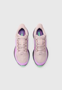 Baskets de sport rose clair avec des accents violets et verts, tige en mesh, bout arrondi, design à lacets et semelle texturée.