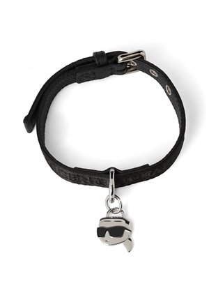 Black leather bracelet with an adjustable buckle, featuring a silver charm of a character wearing sunglasses. Textured strap with patterned detail.