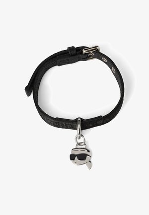 Czarny skórzany bransoletka z regulowanym zapięciem, z zawieszką w kształcie postaci w okularach przeciwsłonecznych. Teksturowany pasek z wzorzystym detalem.