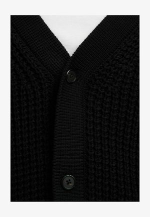 Artimas juodo megztinio su raukšlėtu V formos kaklu ir dviem juodais mygtukais nuotrauka ant baltos fono.
