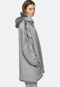 Un sweat à capuche surdimensionné gris en tissu doux et pelucheux. Il dispose d'une grande capuche, de poches latérales et d'un ourlet arrondi pour plus de confort.