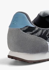 Sportowe sneakersy z fakturowaną czarną siateczką, szarym zamszowym obcasem i niebieskim skórzanym akcentem. Posiadają kontrastującą białą podeszwę środkową oraz gumową bieżnię.