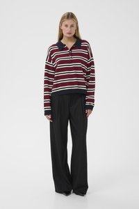 Striped, maroon and cream long-sleeve polo with a dark collar, featuring a button placket and relaxed fit, paired with black wide-leg trousers.
