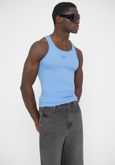 Svetlomodrý rebrovaný tielko s okrúhlym výstrihom a detailom loga, doplnené čiernymi voľnými džínsami s klasickým päťvreckovým dizajnom.