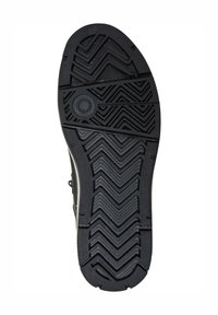 Suela de zapato de goma negra con un patrón de textura que presenta diseños en zigzag y acentos circulares para agarre y tracción.