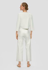 Witte cropped trui met driekwart mouwen, gecombineerd met hoge taille witte wijde jeans, die een zachte textuur en minimalistisch ontwerp laten zien.