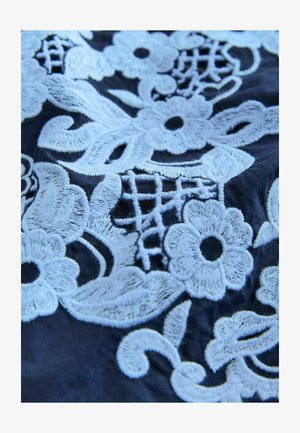 Marineblauer Stoff mit kunstvoller hellblauer Blumenstickerei, Ranken und spitzenähnlichen Mustern. Weiche Textur mit detailreicher Naht.