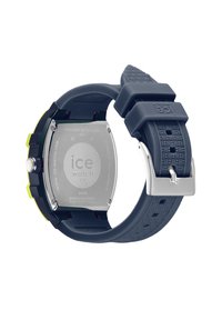 Reloj de silicona azul oscuro con caja rectangular de acero inoxidable, parte trasera plateada y acentos verdes. Presenta una correa texturizada y un cierre seguro.