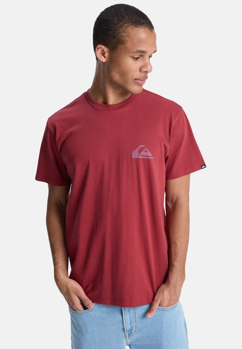 T-shirt en coton rouge avec un col rond, des manches courtes et un petit logo dans le coin supérieur gauche. Le tissu semble lisse.