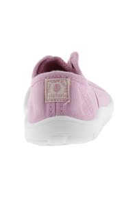 Zapatilla de lona rosa sin cordones con parte superior texturizada, suela de goma blanca y etiqueta de marca en la parte trasera. Diseño simplista con forma curva.