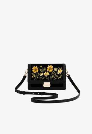 Čierna kožená kabelka cez rameno s vyšívanými žltými a bielymi kvetmi, zlatým zapínaním a nastaviteľným remienkom.