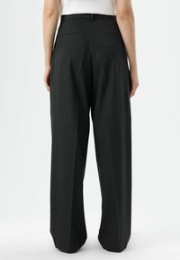 Wijd uitlopende broek in donkergrijze stof. Heeft een getailleerde tailleband, twee achterzakken en een gladde textuur.