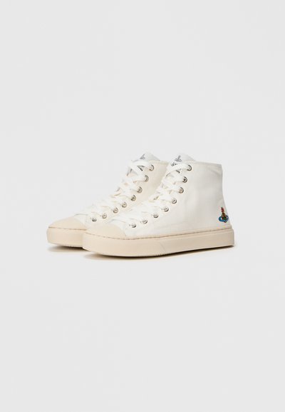Tênis de cano alto em lona off-white com solas de borracha bege, apresentando ilhós prateados e um detalhe bordado colorido na parte externa.